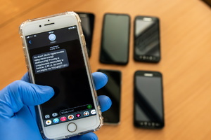 Ręka w rękawiczce trzymająca telefon komórkowy z wiadomością SMS